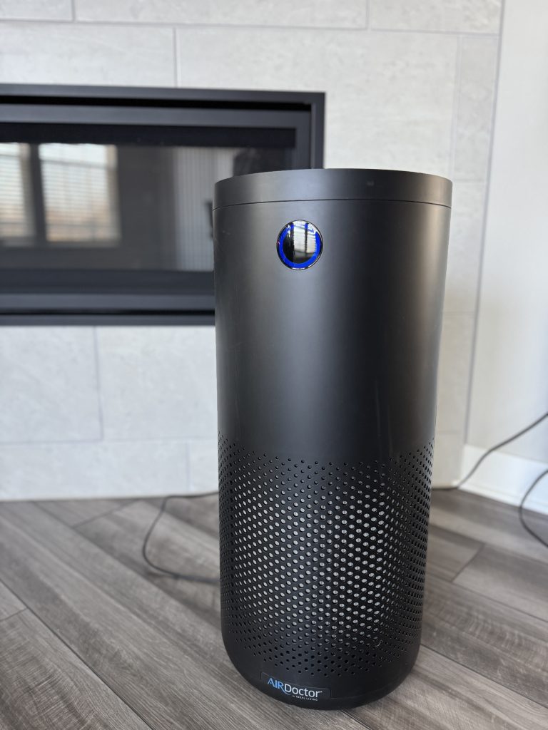 AirDoctor 4000 air purifier standing in a living room near a fireplace