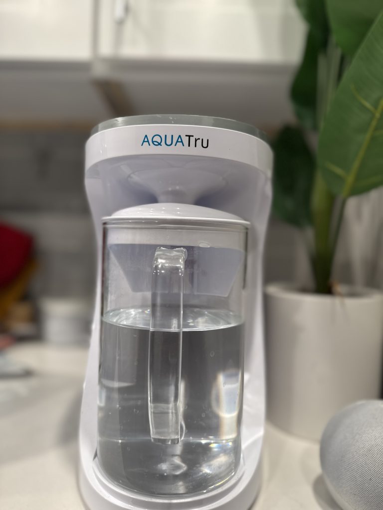 AquaTru water filter review close-up of the AquaTru Carafe filled with filtered water on a kitchen counter.