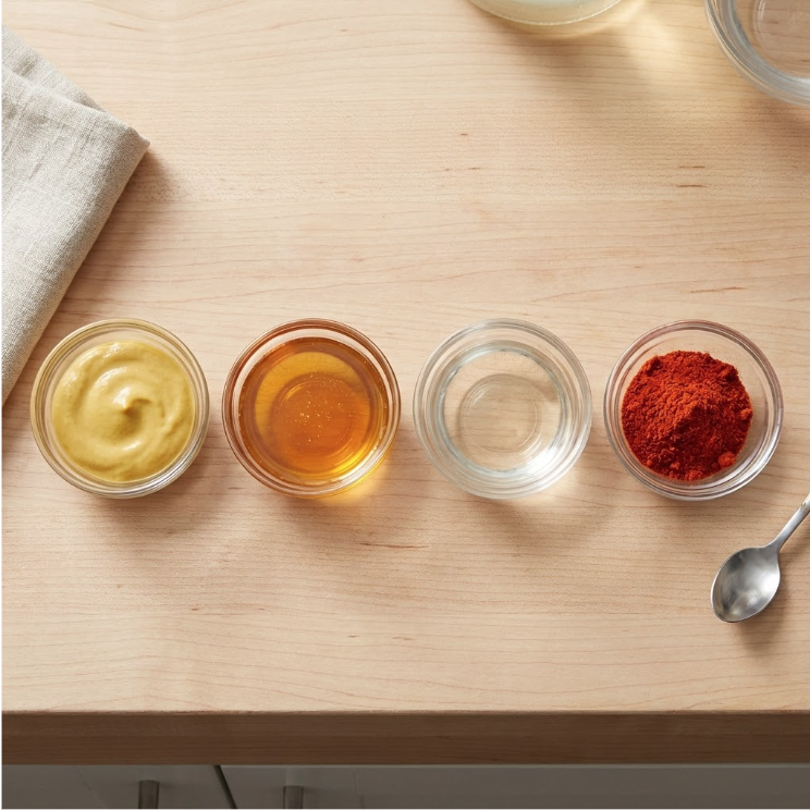 Overhead view of homemade honey mustard ingredients in small glass bowls