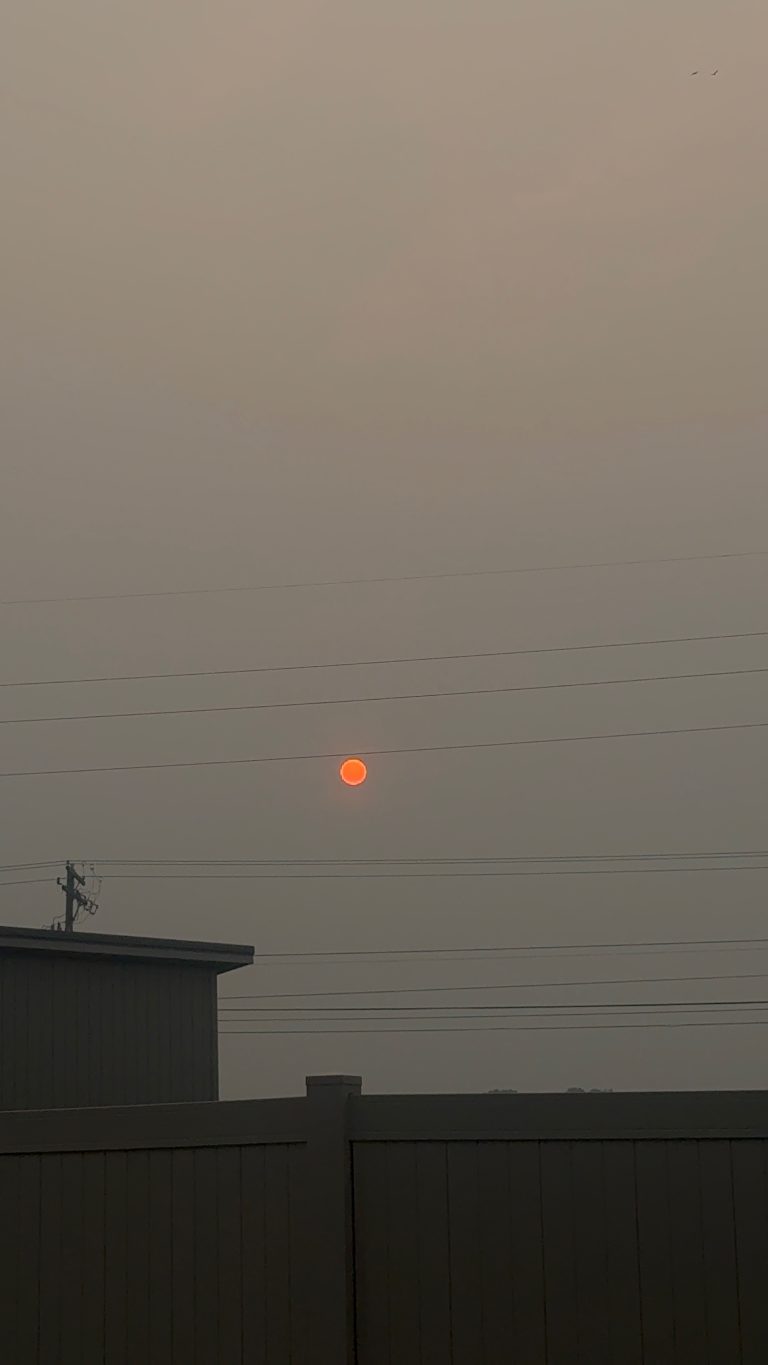 Hazy orange sky from wildfire smoke blocking the sun during hazardous AQI event